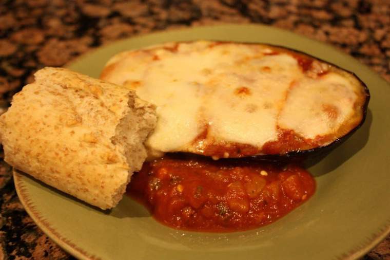 Eggplant Parmesan stuffed eggplant on plate with a roll