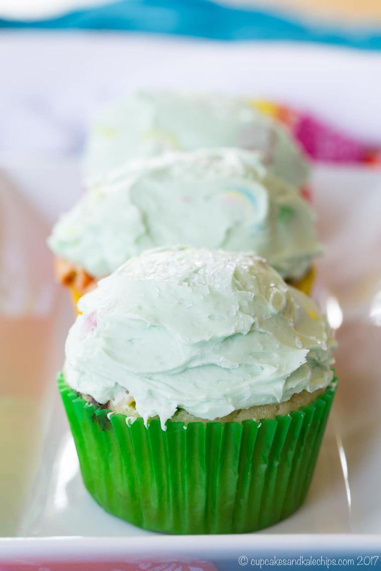 three lucky charms cupcakes on a white rectangular plate
