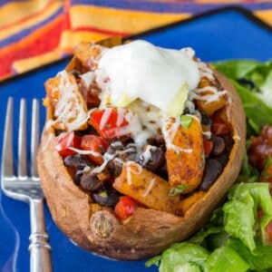 A Mexican Sweet Potato with black bean pineapple filling and shredded cheese, avocado, and sour cream on top.