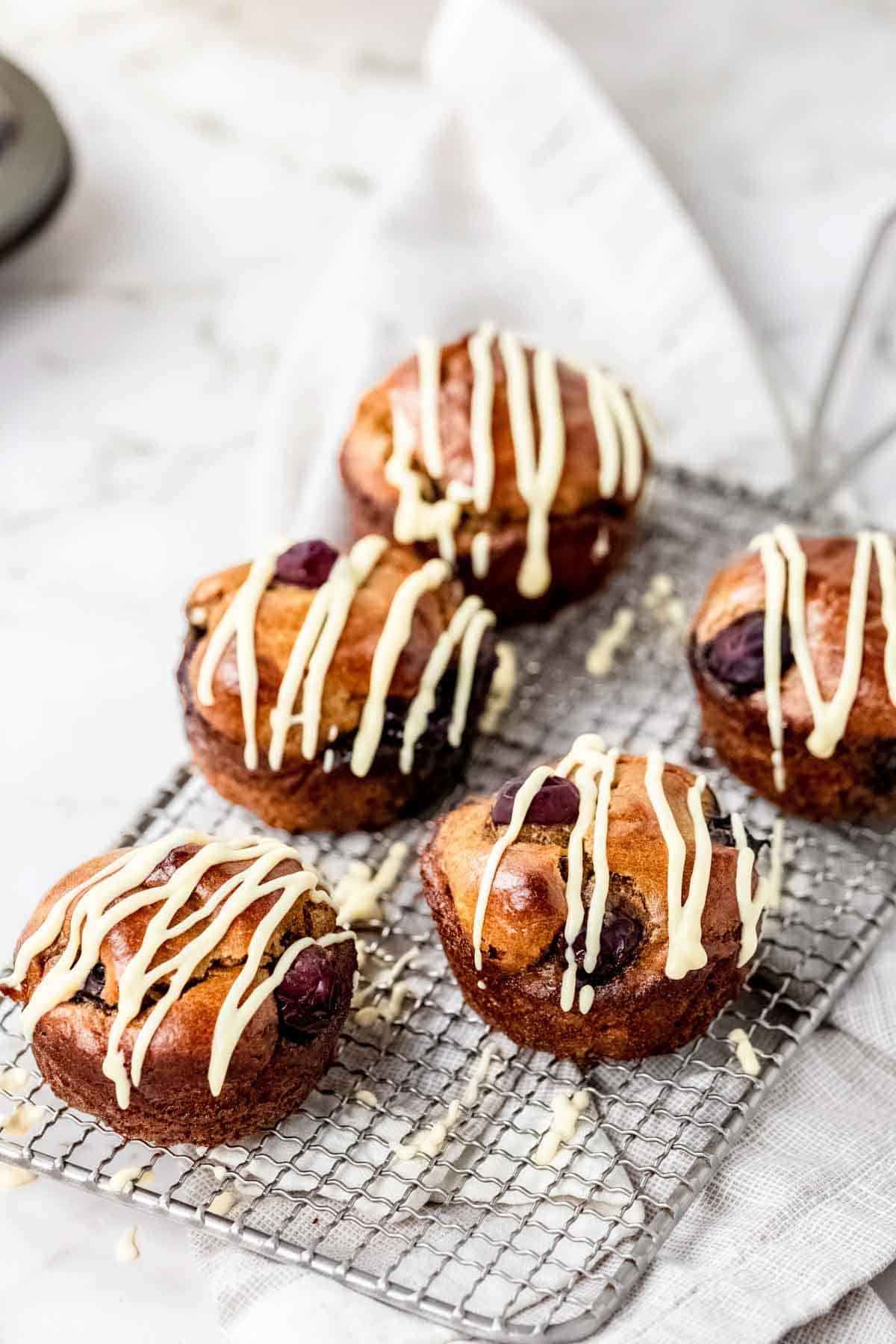 Flourless blueberry mini muffins on a wire rack, drizzled with maple cream cheese.