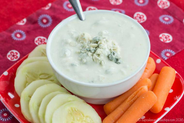 A bowl of Greek Yogurt Blue Cheese Dip on a plate with carrots and cucumbers