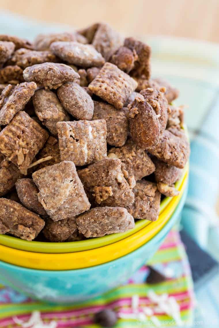 Three stacked colorful bowls with the top one full of a chocolate-covered Chex mix.