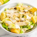 Chicken Caesar Salad in a white salad bowl with a fork