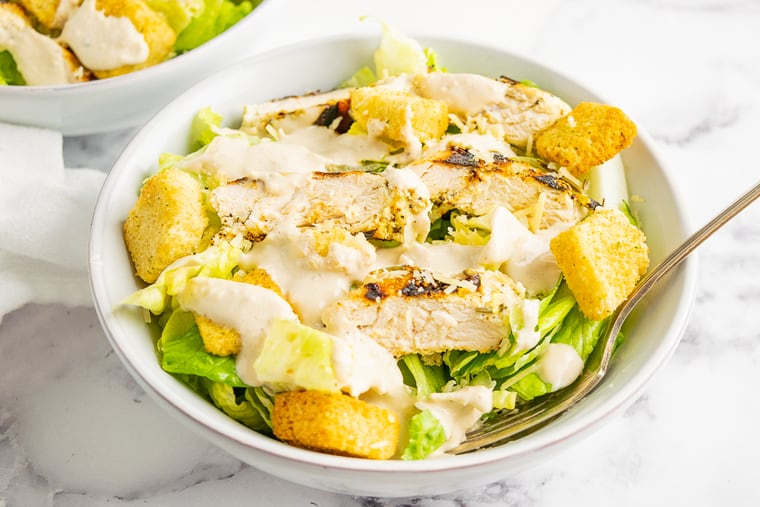 Chicken Caesar Salad in a white salad bowl with a fork