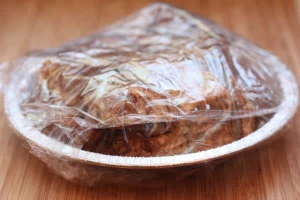 A plate of gooey bars wrapped in plastic wrap.