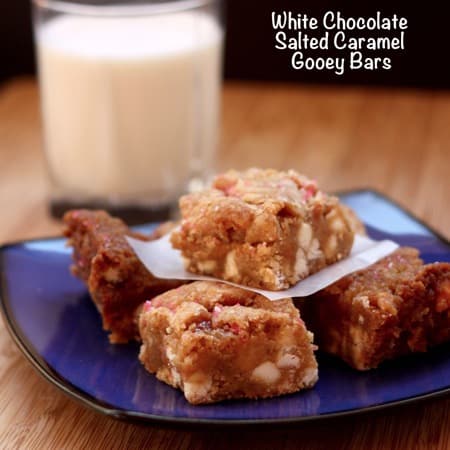 Three gooey bars stacked on a dark blue plate with a glass of milk in the background.