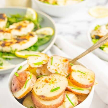 A bowl of Foil Packet Potatoes on a table with other dishes.