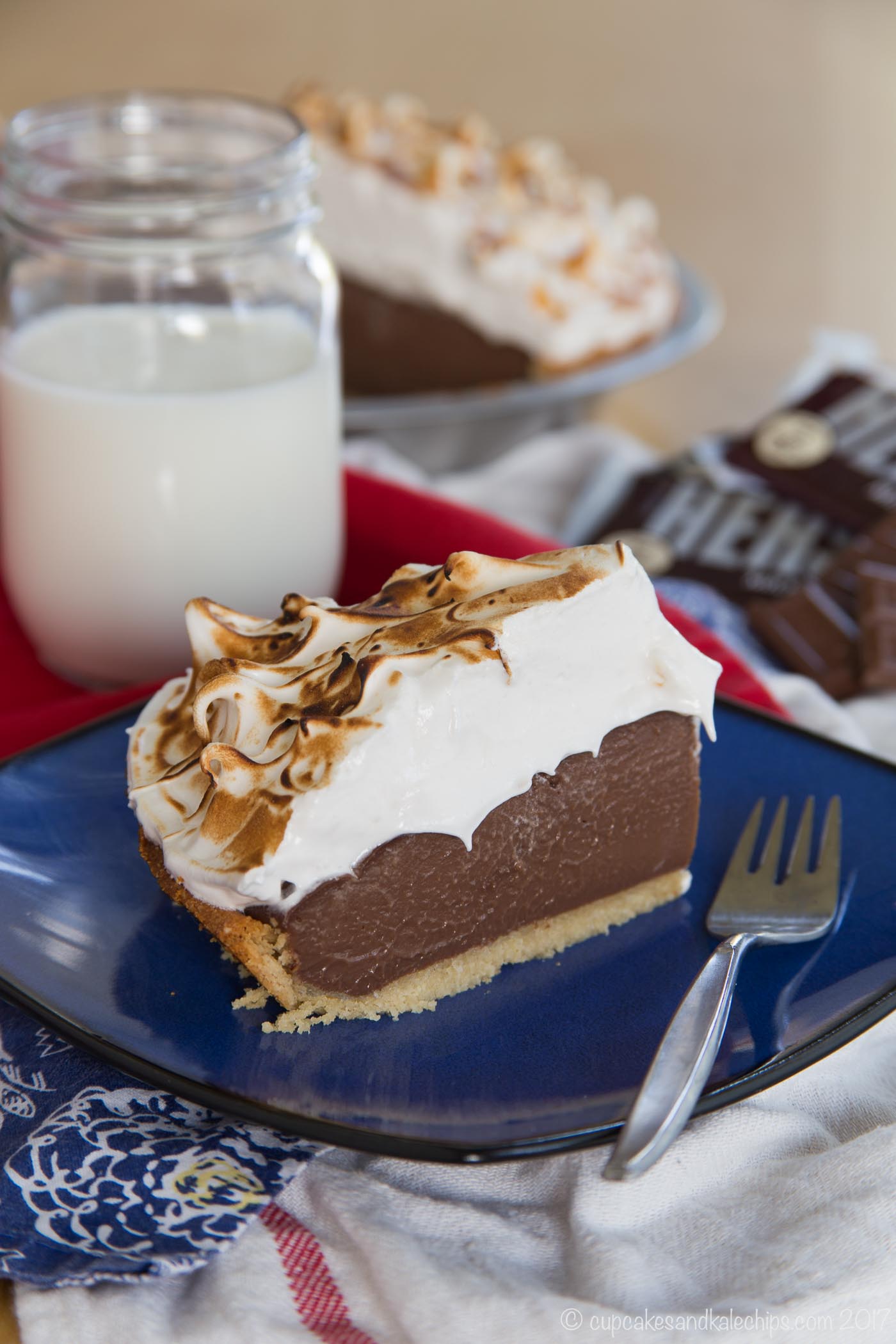 A slice of s'mores pudding pie on a blue plate next to a fork.