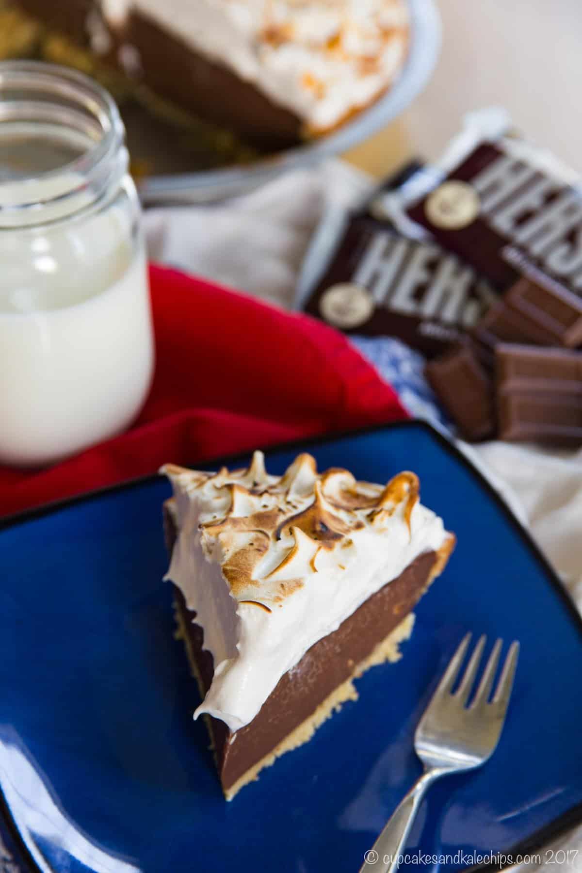 A slice of s'mores pudding pie on a blue plate next to a fork.