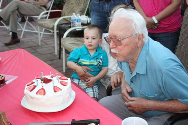 Grandpa blowing out birthday candles on this cake