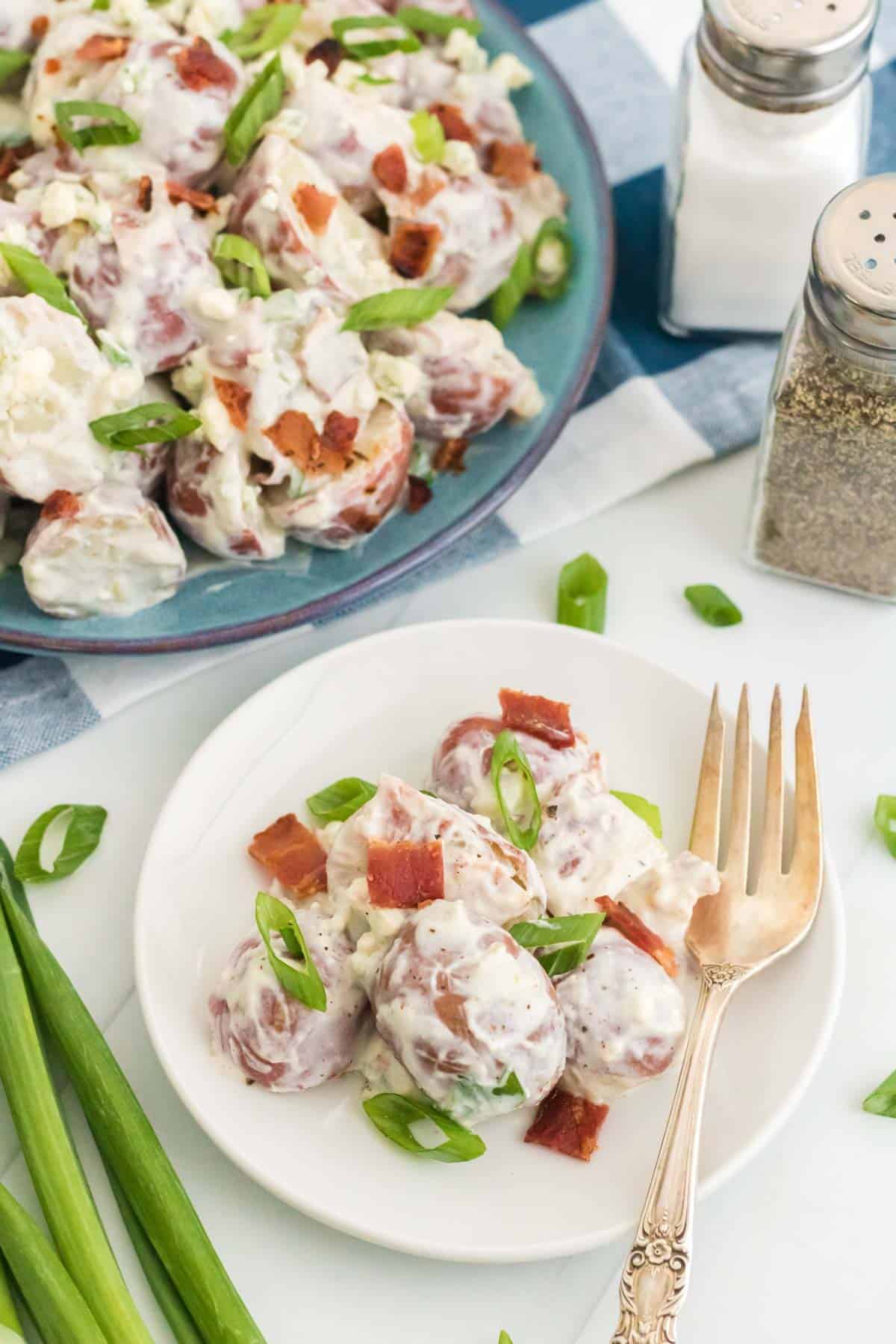 A small plate of bacon potato salad next to the remaining salad.