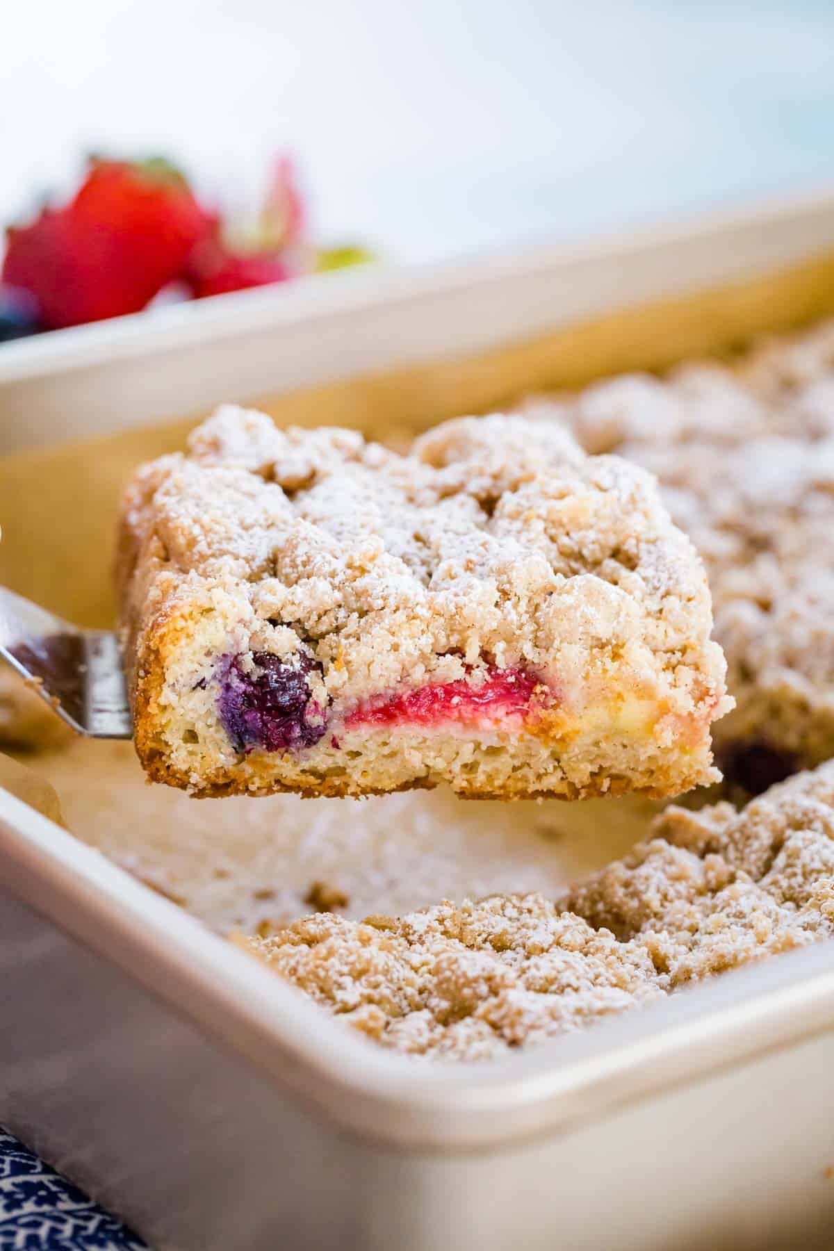 A slice of crumb cake is lifted from the rest of the cake in a baking pan.