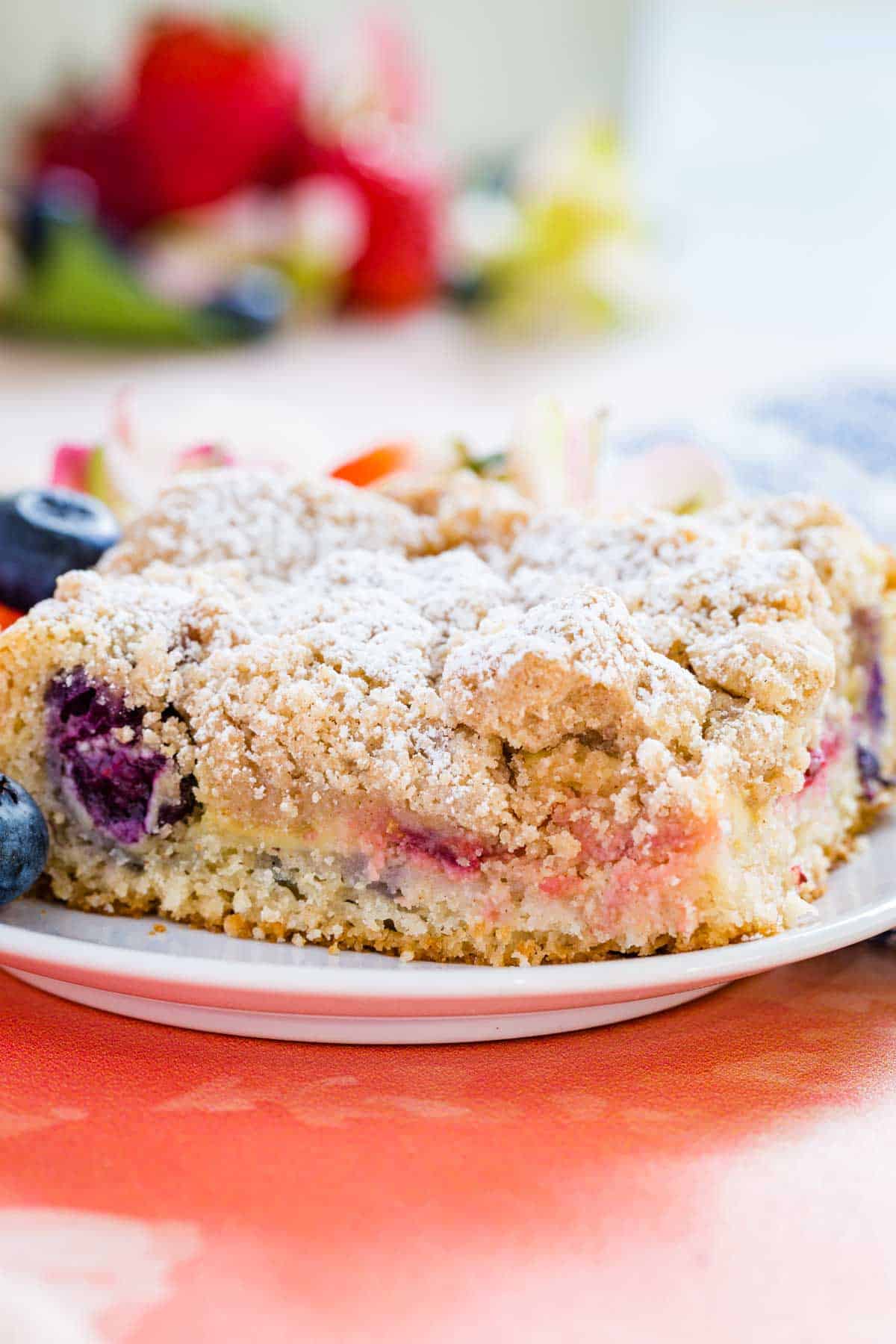 A slice of strawberry and blueberry crumb cake served on a plate.