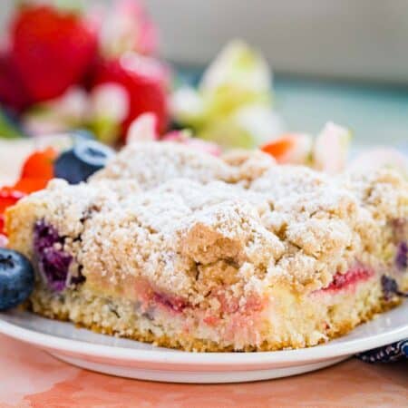 Close up of a slice of strawberry and blueberry crumb cake served on a plate.