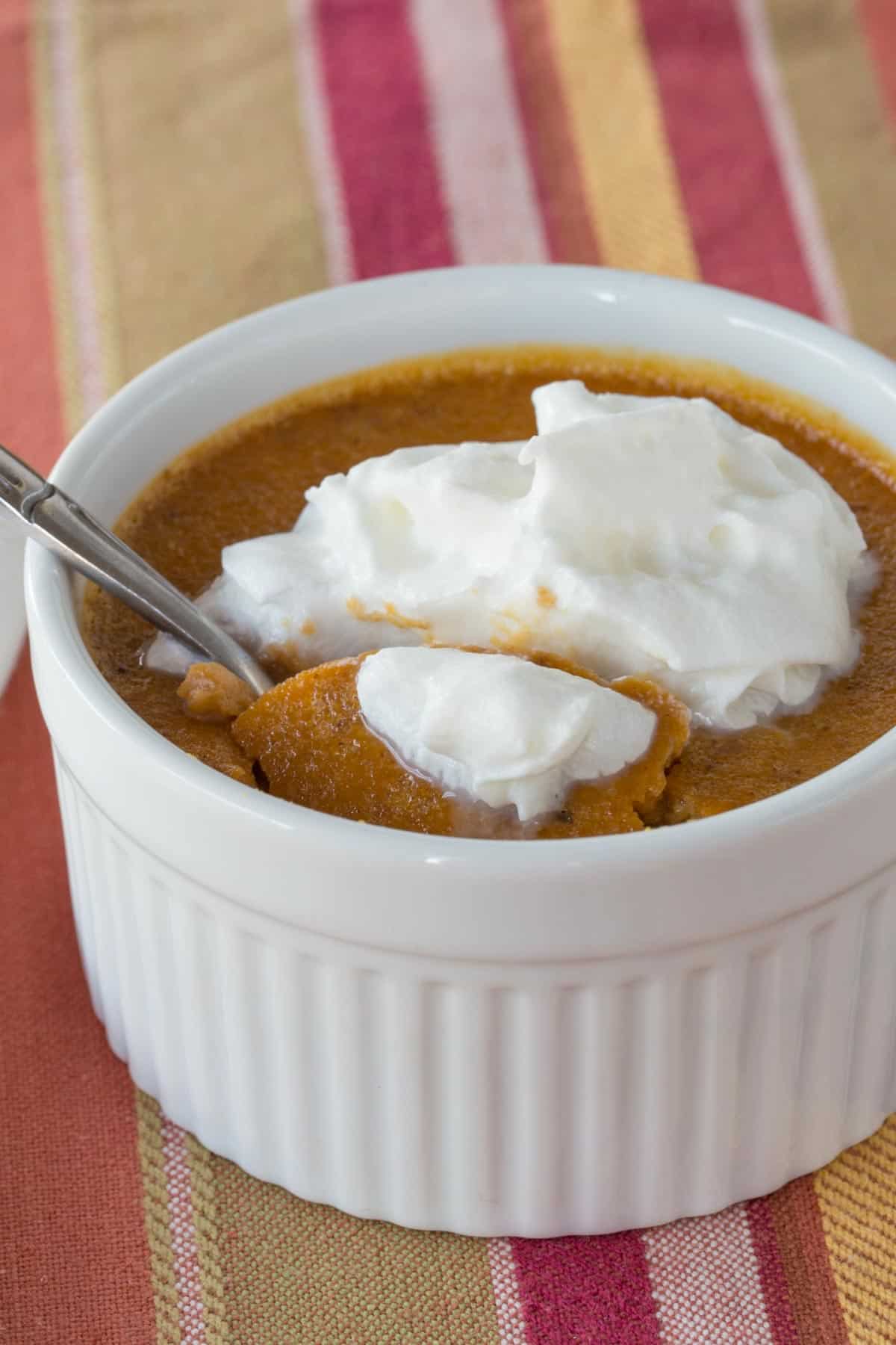 using a spoon to get a bite of crustless pumpkin pie with whipped cream