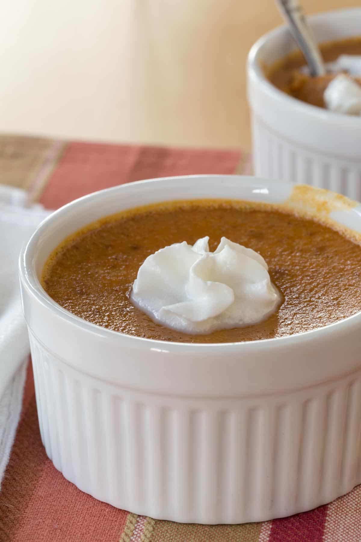 mini crustless pumpkin pie in a ramekin topped with a small spritz of whipped cream