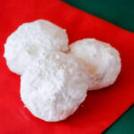 Three snowball cookies on a red napkin and green tablecloth