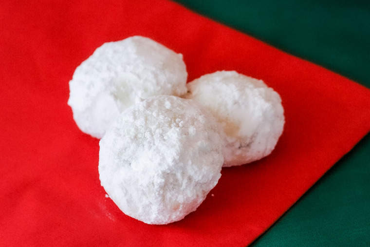 Three snowball cookies on a red napkin and green tablecloth