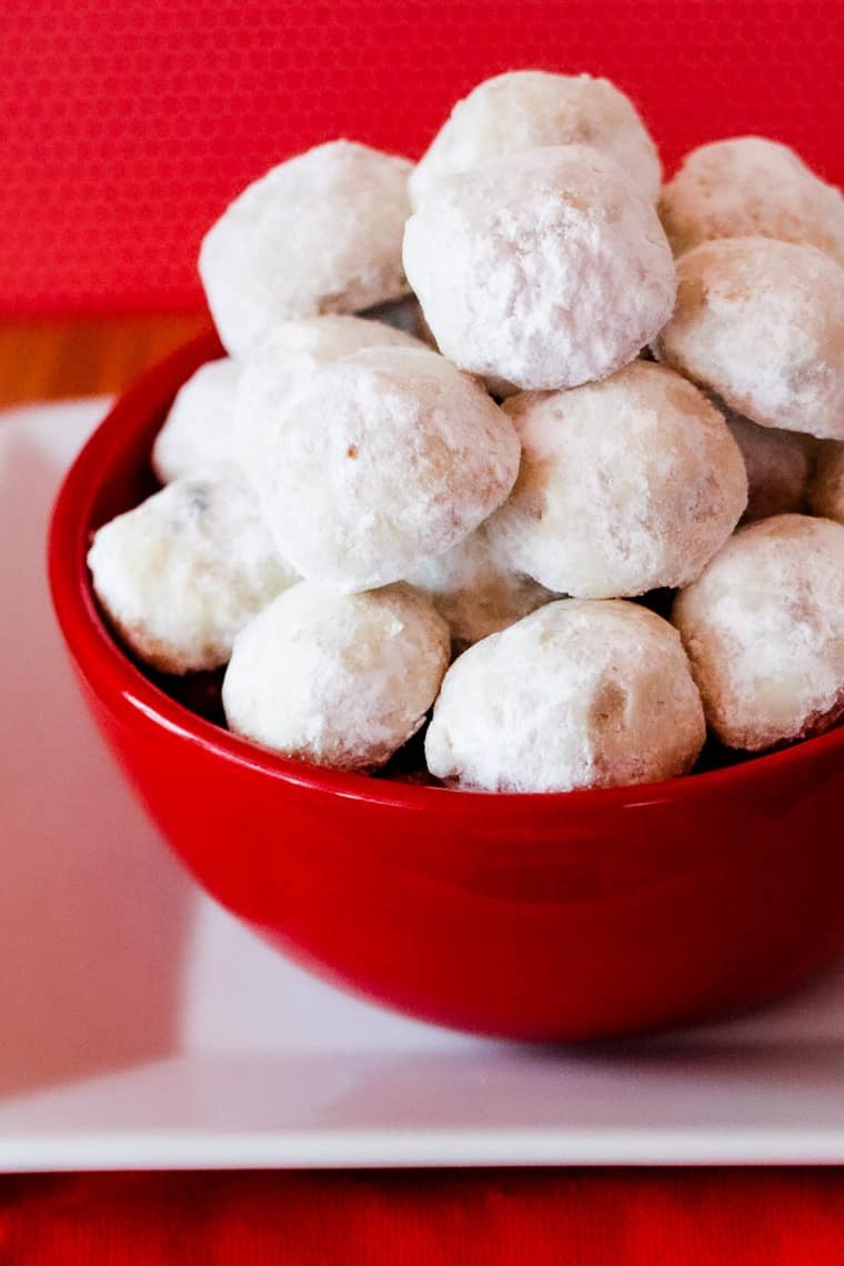 A red bowl filled with snowball cookies