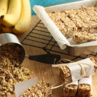 Banana nut breakfast granola bars next to a oats spilling from a measuring cup.