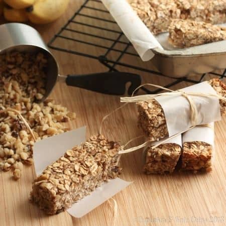 Banana nut breakfast granola bars next to a oats spilling from a measuring cup.