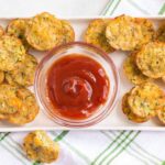 Zucchini Potato Tots on a rectangular platter with a bowl of ketchup