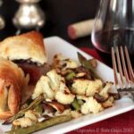 Roasted cauliflower, green beans, and mushrooms with blue cheese on a plate.