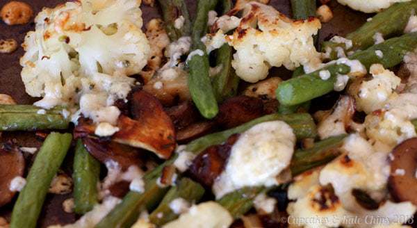 Close up of roasted cauliflower, green beans, and mushrooms with blue cheese.