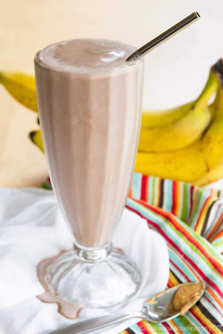 Chocolate Smoothie in a tall glass with bananas and a spoon of peanut butter
