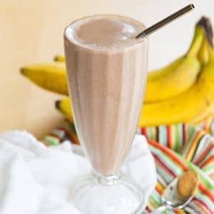 A chocolate peanut butter banana smoothie in a tall milkshake glass.