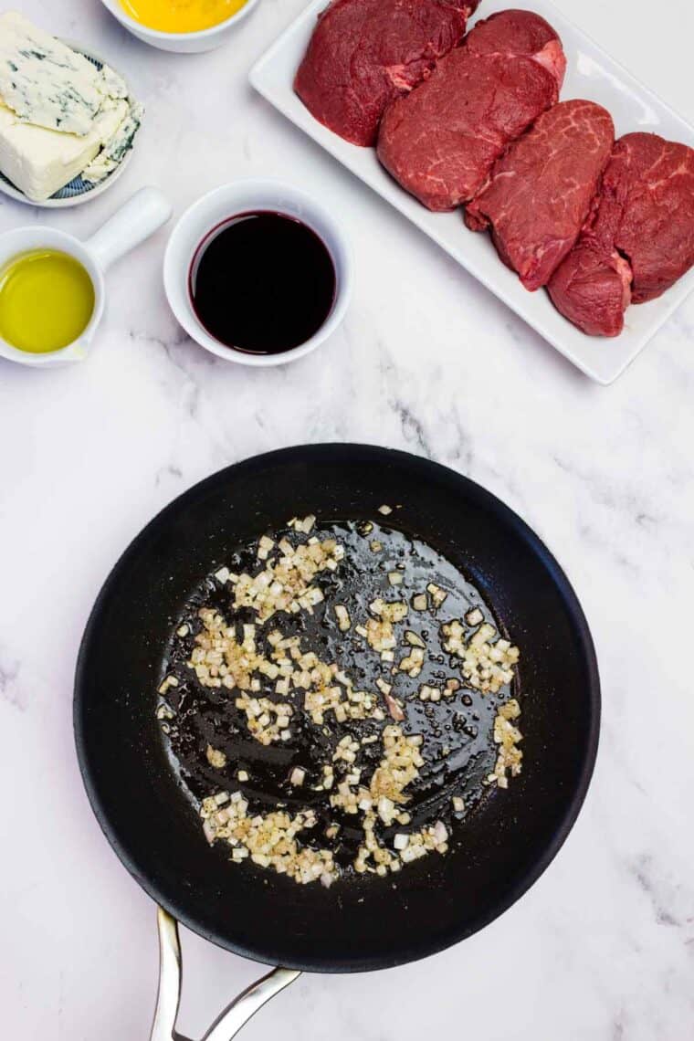 Shallots sauteing in a cast iron skillet