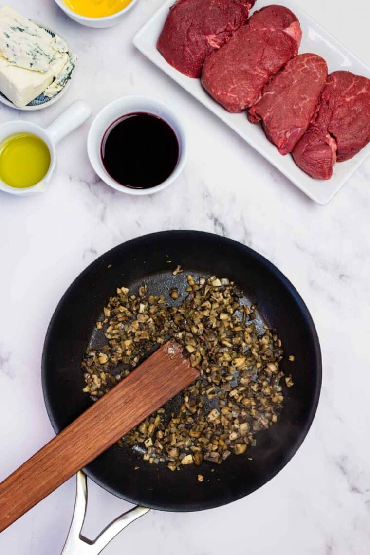Stirring sauteed mushrooms in a cast iron skillet