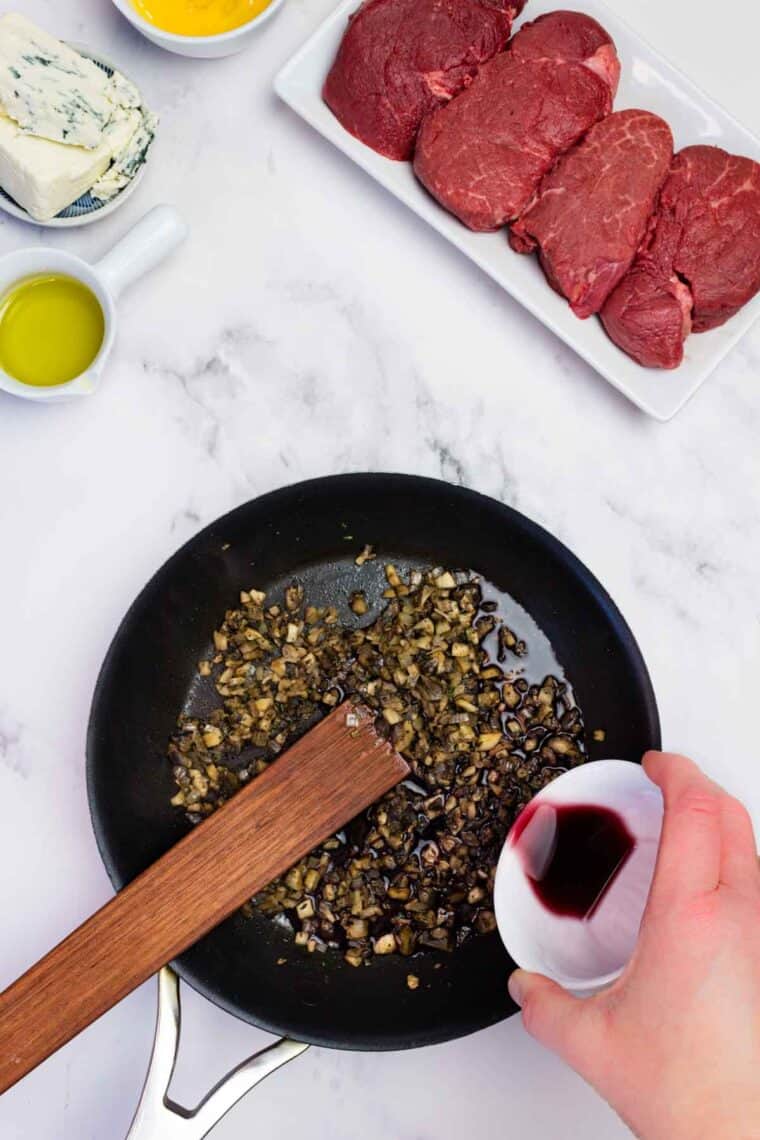 Adding red wine to sauteed mushrooms in a cast iron skillet