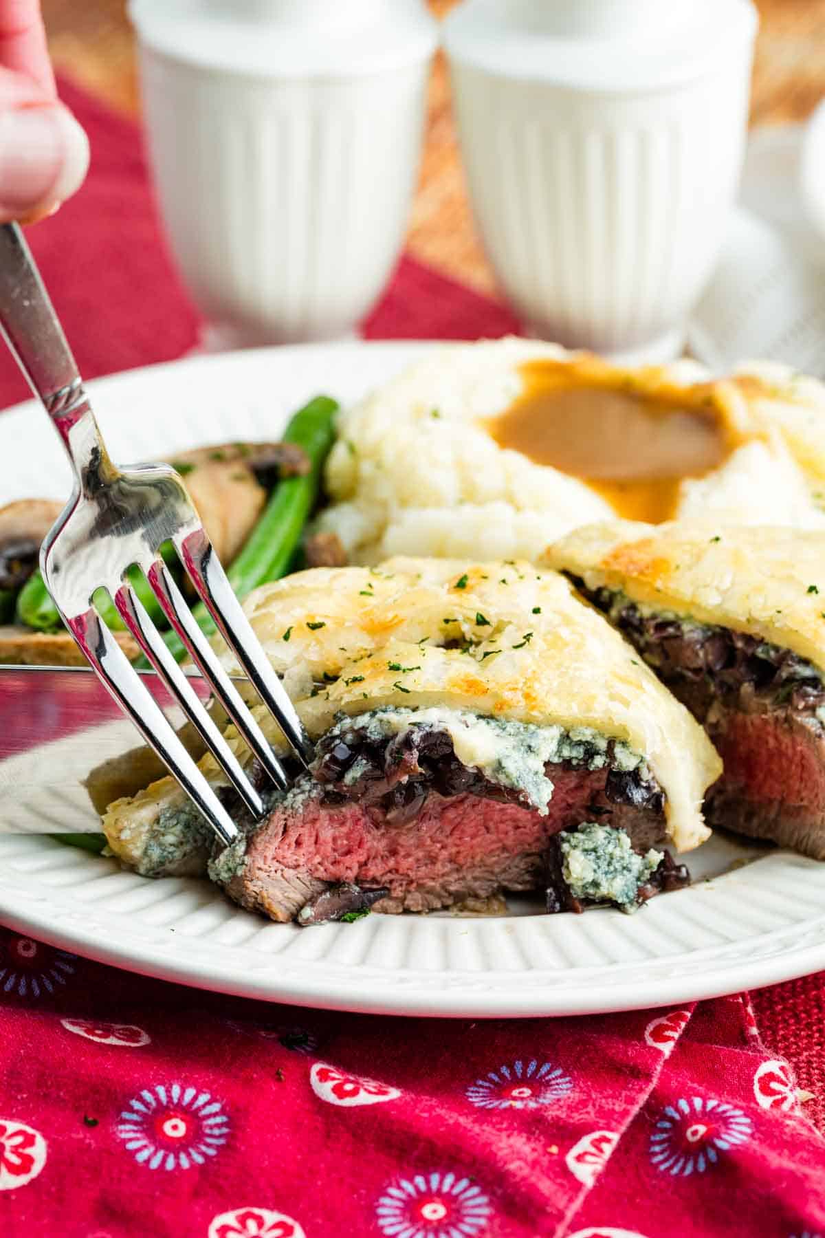 A fork cutting into Individual Beef Wellington on a plate