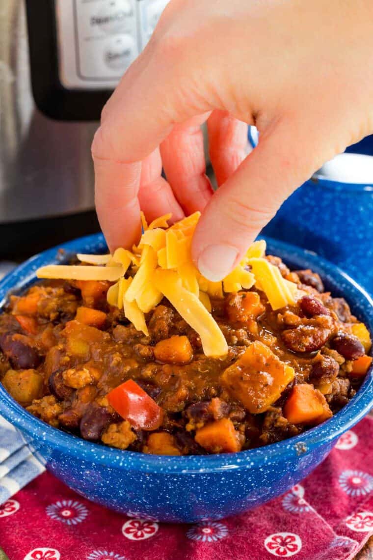 A bowl of Aloha chili is sprinkled with shredded cheese.