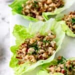 Close up of Thai larb chicken lettuce wraps on a white stone cutting board.