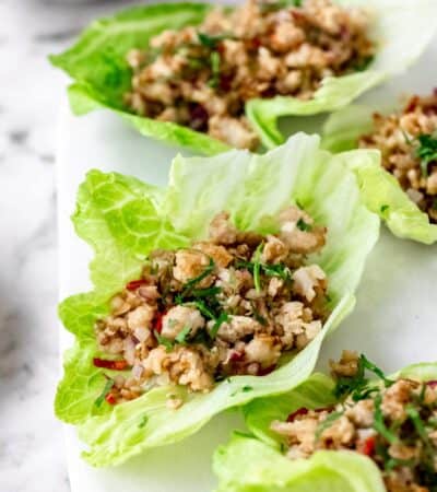 Close up of Thai larb chicken lettuce wraps on a white stone cutting board.