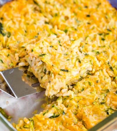 Scooping up a piece of zucchini rice casserole out of the baking dish