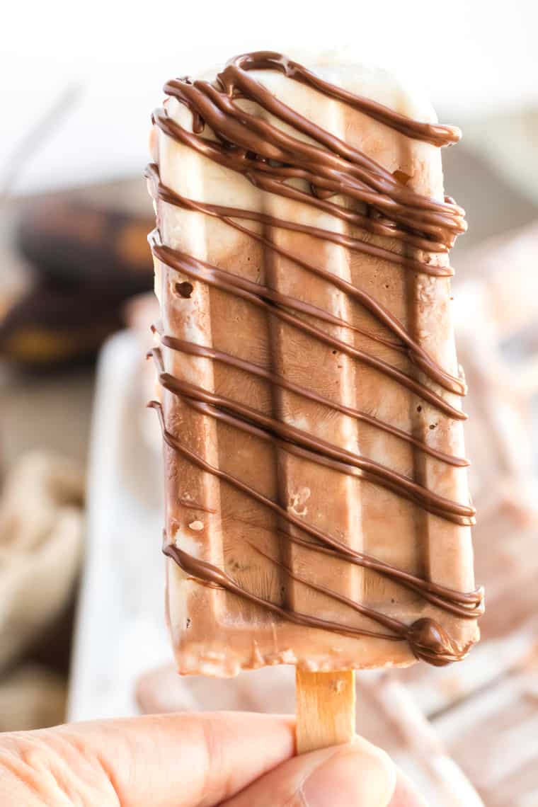 Greek Yogurt Nutella Banana Popsicle Drizzle with Nutella being held in a hand