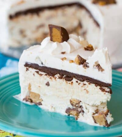 A slice of Reese's peanut butter ice cream cake on a plate with the rest of the cake behind it.