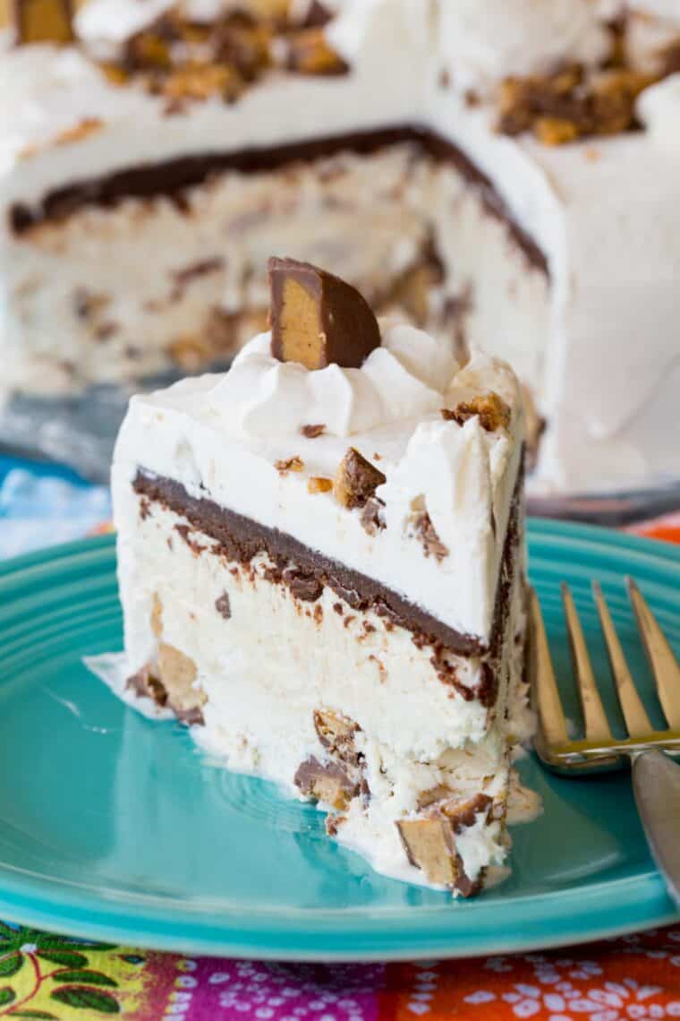 pieces of reeses ice cream cake with a layer of peanut butter cup-filled ice cream, a layer of chocolate ganache. and covered in whipped cream