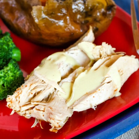 Pieces of Crock Pot Turkey Breast with sauce on a red plate