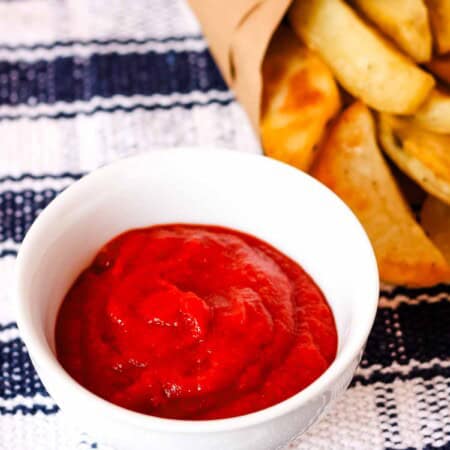 Homemade Ketchup in a bowl with some French fries in the background.