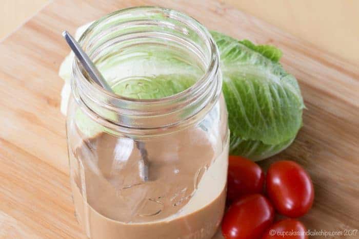 Homemade Creamy Balsamic Vinaigrette on a cutting board with lettuce and tomatoes