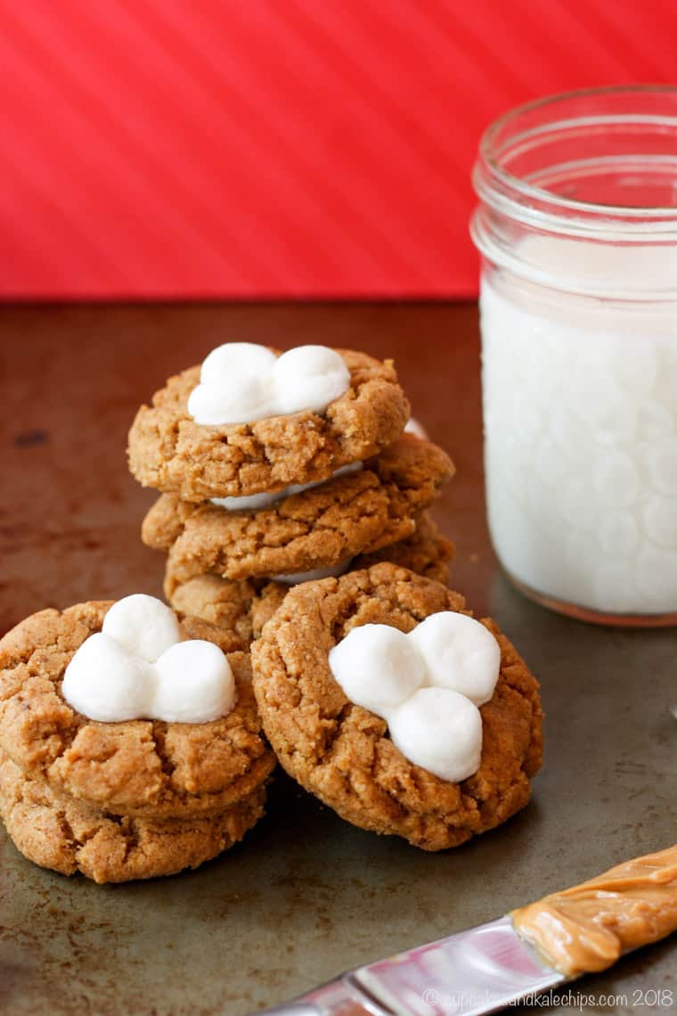 Flourless Fluffernutter Cookies with a glass of milk against a red background