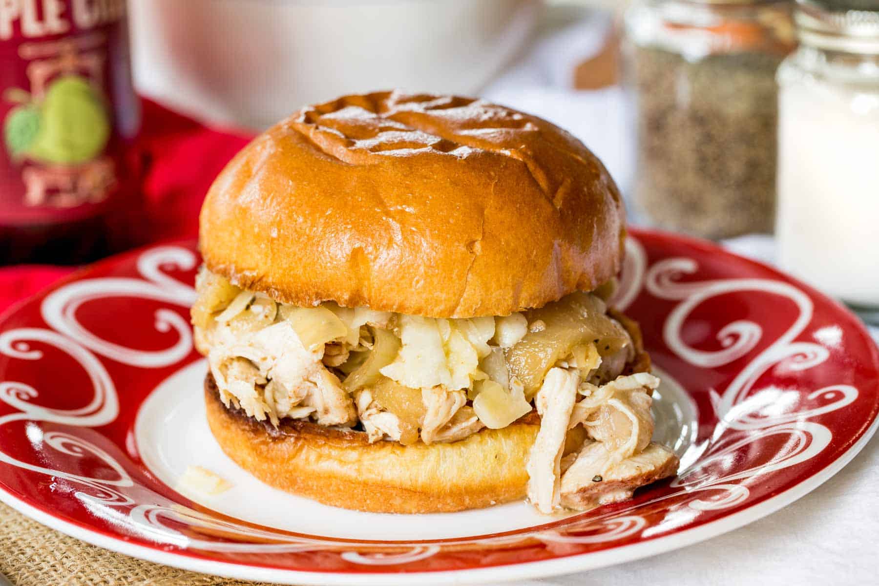 Slow Cooker Apple Cider Pulled Chicken Sandwich on a red and white plate