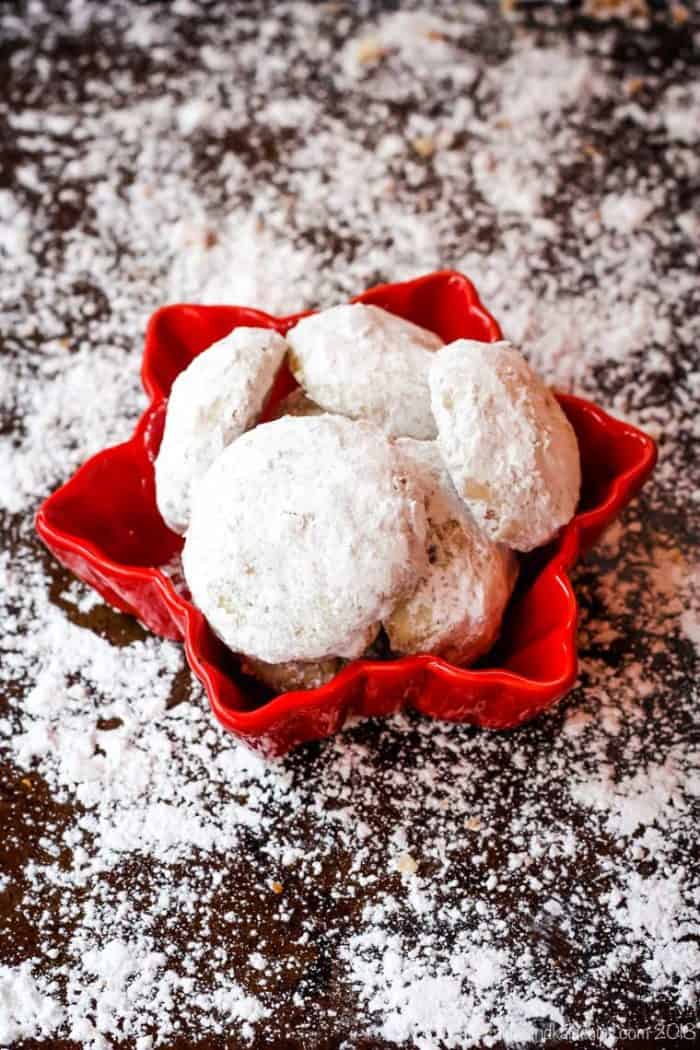 Toffee Almond Snowball Cookies in a snowflake bowl with powdered sugar