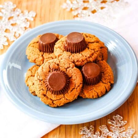 Reese's-topped peanut butter cookies on a blue plate in top of a white napkin.