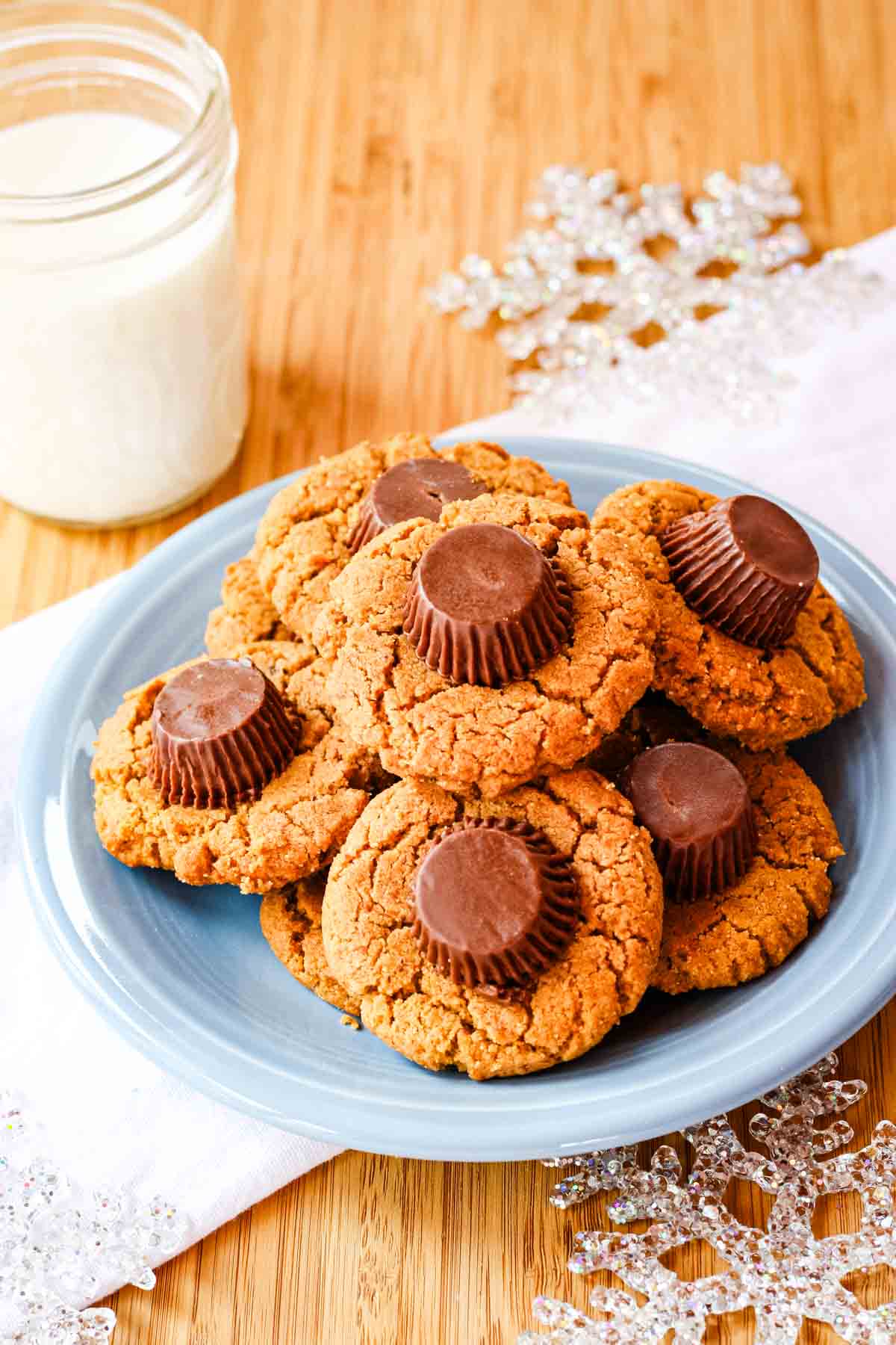 Reese's peanut butter cookies on a blue plate in top of a white napkin with a galss jar of milk.