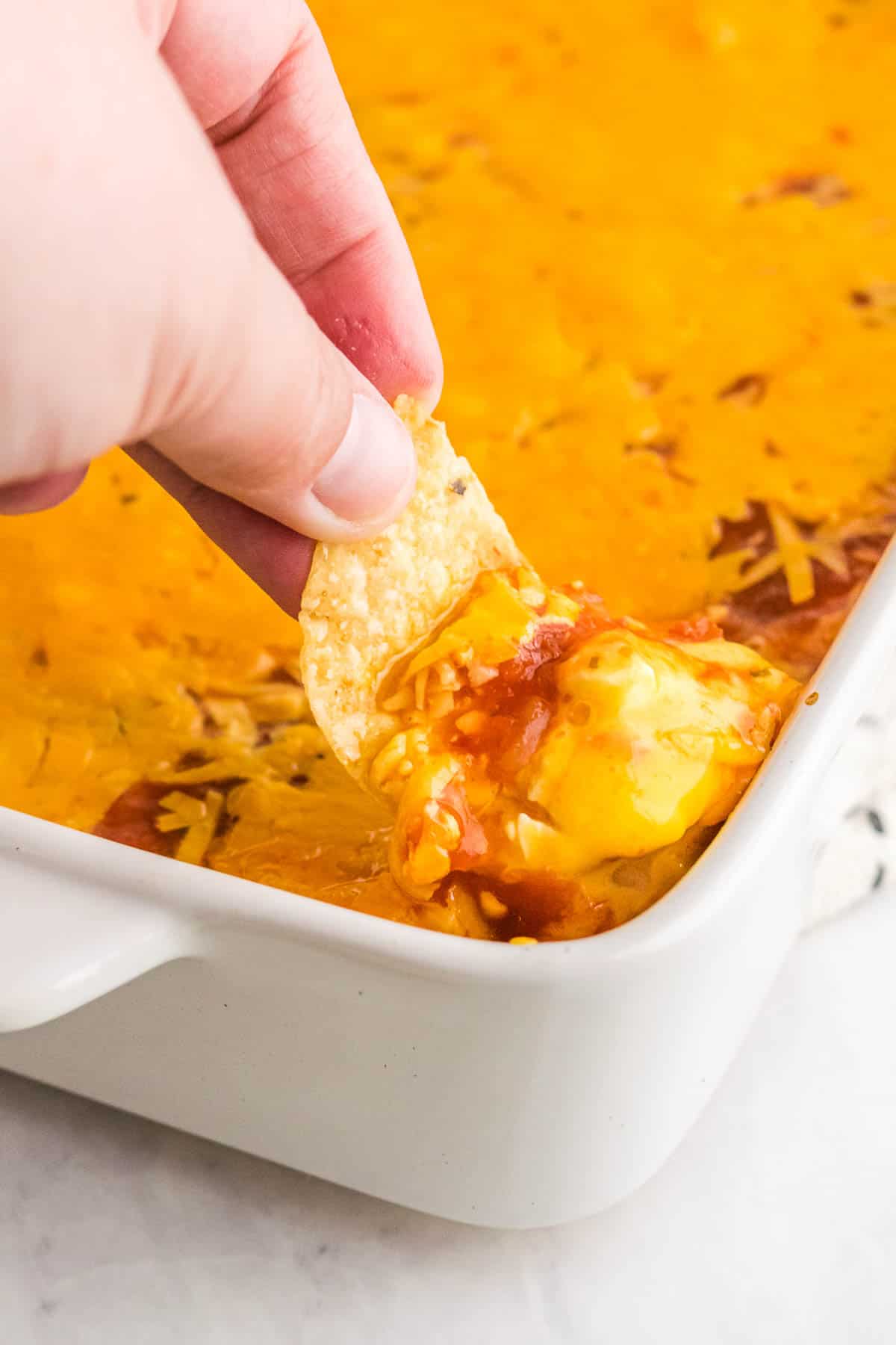 Dipping a tortilla chip into layered Mexican dip